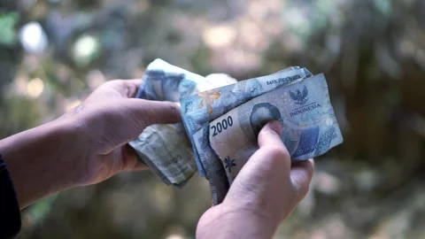 Of hands holding a stack of two thousand Indonesian Rupiah banknotes. Stock Footage 345973546