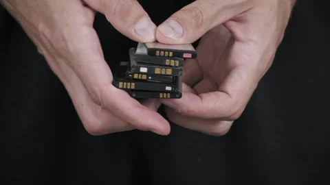 Hands Holding a Stack of Used Lithium-Ion Mobile Phone Batteries Stock Footage 315773789