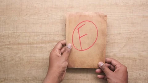 Hands holding stack of vintage paper with red grade f letter mark showing f.. Stock Footage 332032289