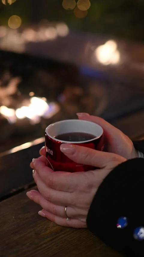 Hands Holding a Steaming Hot Drink by the Fire at a Christmas Market Видео 318204262