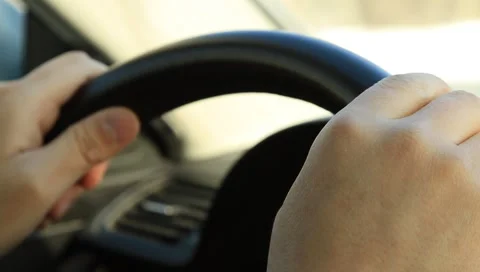 Hands holding the steering wheel of a car and tapping fingers in Moscow city Stock Footage