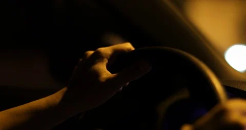 Hands holding steering wheel driving at night in 4K slow-motion. Lights passi Stock Footage 119250131