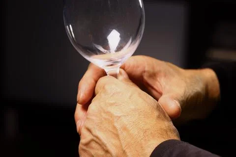 Hands Holding the Stem of an Empty Wine Glass in Soft Light Stock Photos