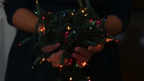 Hands holding a string of blinking colorful holiday Christmas lights Stock Footage 163935916