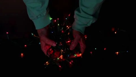 Hands holding a string of blinking colorful holiday Christmas lights Stock Footage 163935927