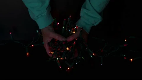 Hands holding a string of blinking colorful holiday Christmas lights Stock Footage 163935935