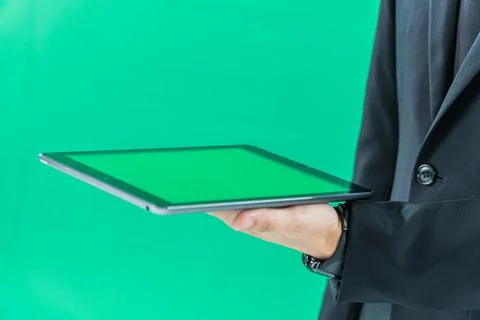 Hands holding tablet computer on light green background Stock Photos