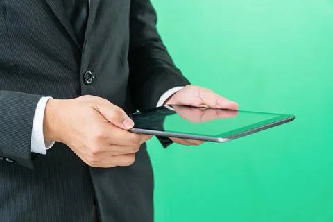 Hands holding tablet computer on light green background Foto stock
