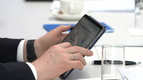 Hands holding tablet. Hand scrolls screen with finger. White table, glass, pens Stock Footage 229854802