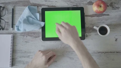 Hands holding tablet pc with green empty screen on wooden background Stock Footage 80246113