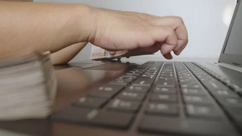 Hands holding of thousands Thai baht banknotes money and working with laptop. Stock Footage 236014622