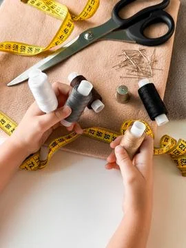 Hands holding thread and sewing tools on fabric with measuring tape and scissors Stock Photos