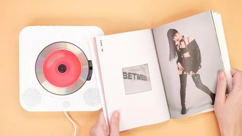 Hands holding Twice Between 1 and 2 mini Album photobook on yellow. Music C.. Stock Photos