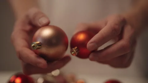 Hands holding two Christmas baubles, vibrant red and subtle rose gold, 스톡 동영상 327475575
