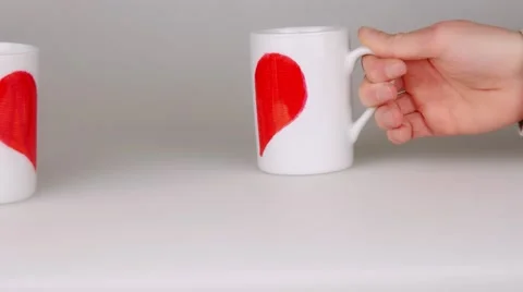 Hands holding two coffee cups painted with halves red heart shape. Stock Footage 59532156