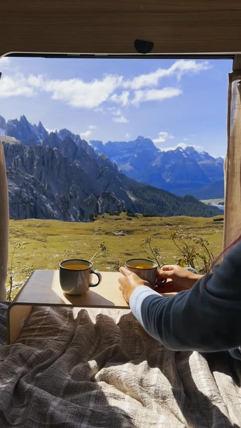 Hands holding two cups of tea with window view of Tre Cime mountains. Stock Footage 330437464