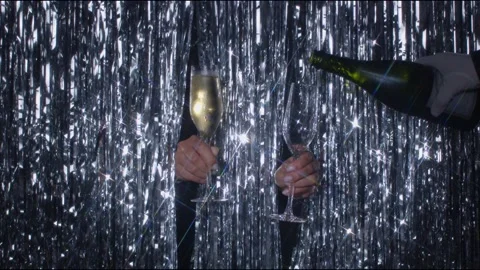 Hands holding two glasses of champagne on a shimmery background. Another hand Stock Footage 146168979