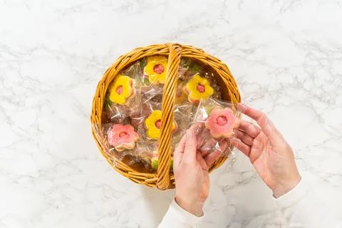 Hands Holding Two Packaged Cookies Over Basket Photos