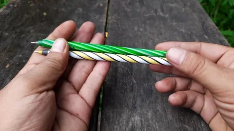 Hands Holding Two Striped Ballpoint Pens on Wooden Table Stock Footage 310263412