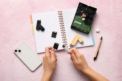 Hands holding a usb flash drive and sd card with various data storage devices Stock Photos