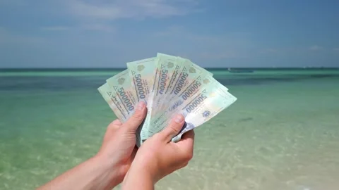 Hands holding Vietnamese Dong on tropical beach in Vietnam. Close up 스톡 동영상 263390953