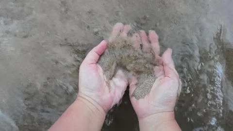Hands holding wet sand at the edge of the beach Stock Footage 340004794