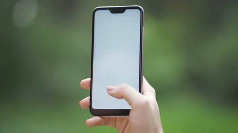 Hands holding white screen smartphone on blurred abstract green nature Stock Footage 151745625