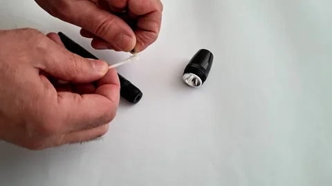 Hands Holding White Wick with Flashlight Components on Clean White Surface 動画素材 332890570