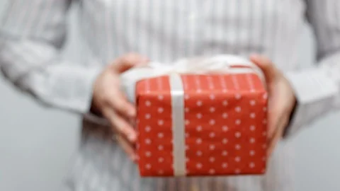Hands holding wrapped present, gift box with ribbon and bow. Holidays packaging. Video stock 117191238