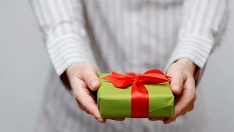 Hands holding wrapped present, gift box with ribbon and bow. Holidays packaging. Stock Footage 117191753