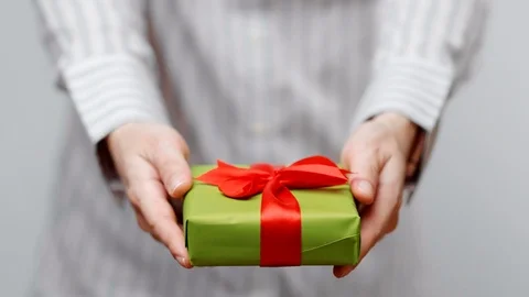 Hands holding wrapped present, gift box with ribbon and bow. Holidays packaging. Stock Footage 117191868