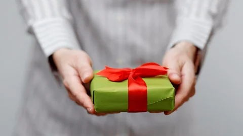 Hands holding wrapped present, gift box with ribbon and bow. Holidays packaging. Stock Footage 117191915