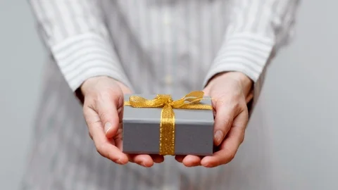 Hands holding wrapped present, gift box with ribbon and bow. Holidays packaging. Stock Footage 117192175
