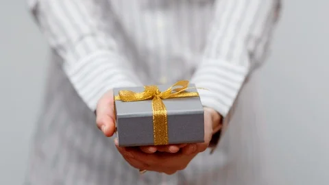 Hands holding wrapped present, gift box with ribbon and bow. Holidays packaging. Stock Footage 117192183