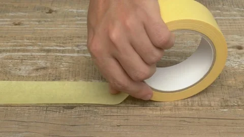Hands holding yellow tape on table, for DIY, crafting, renovation, and repair Stock Footage 279897813