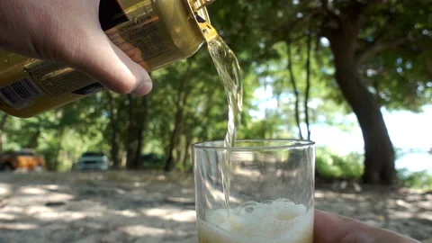 Hands holds an open can of beer and pours it into a glass in slow motion Video stock 137028669