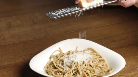 Hands of home chef grating cheese above pesto pasta spaghetti. Italian food. Stock Footage 302019564