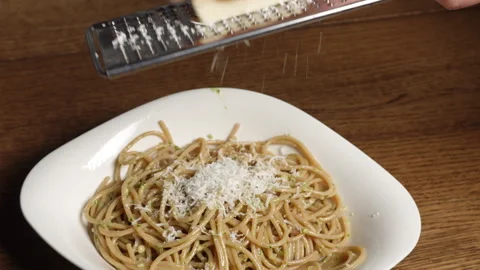 Hands of home chef grating cheese above pesto pasta spaghetti. Italian food. Stock Footage 302019601