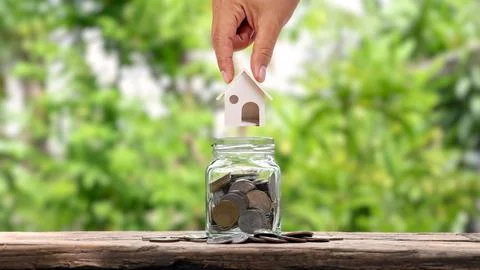 Hands that house models put in a jar for savings, money-saving ideas to buy.. Stock Photos
