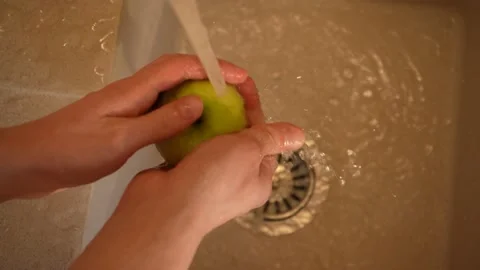 Hands of a housekeeper washes an apple in the kitchen sink close-up top view 4K Stockbeeldmateriaal 195280565