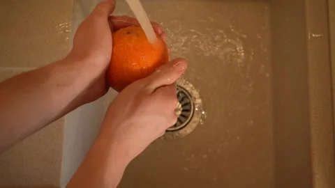 Hands of a housekeeper washes an orange in the kitchen sink close-up top view 4K Stock-Footage 195280472