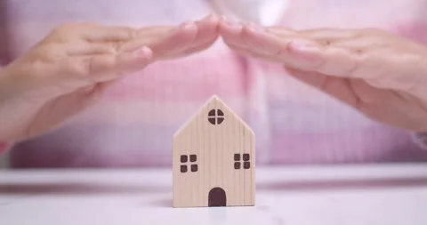 Hands hovering over a tiny wooden house manifesting a desire of owning a Vídeo Stock 261165174