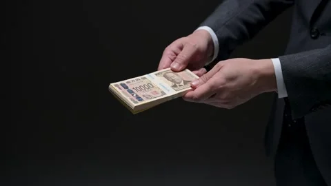 Hands illicitly exchanging a bundle of new Japanese yen bills Stock Footage 336765786