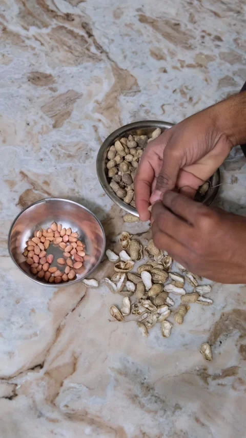 Hands of an Indian man cracking shells of roasted peanuts Stock Footage 330876611