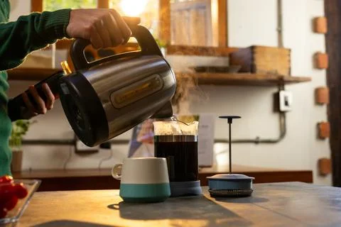 Hands of indian man making coffee and using smartphone in kitchen at home Fotos de archivo