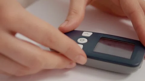 Hands insert blood glucose strip for monitoring sugar levels at home Stock Footage 346703419
