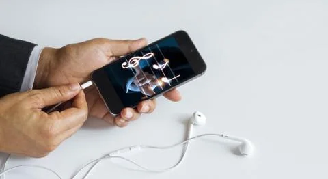 Hands insert earphone jack to smartphone with music on screen Fotos Stock