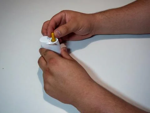 Hands Inserting a Capsule into a White container on White Background Stock Photos