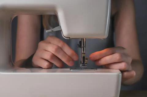 Hands inserting thread into hole of needle in sewing machine 写真素材
