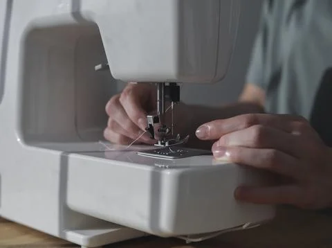 Hands inserting thread through needle hole in sewing machine Foto stock